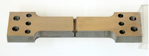Figure 5 SENT specimen design with bolt holes (a) which can be gripped inside a thermal chamber