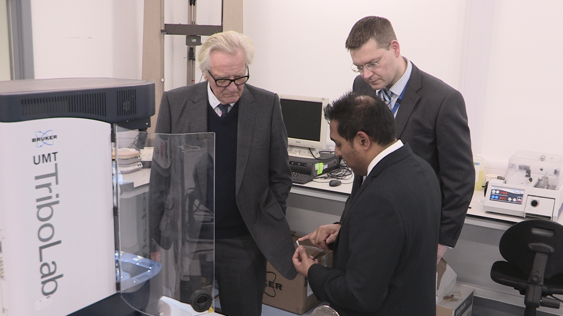 TWI's Amit Rana demonstrates the effects and measurement of frictional force on surfaces in constant contact with Lord Heseltine and TWI Operations Director Mike Russell