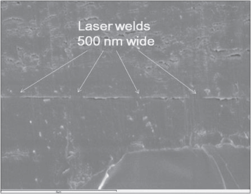 Fig. 6 Laser welded sample in cross section. The tops of the 5 μm wide tracks have been welded to the top sheet of PMMA. Gaps with a height of a few hundred nanometres have been left on either side of the welded tracks. (scale bar 6 μm).