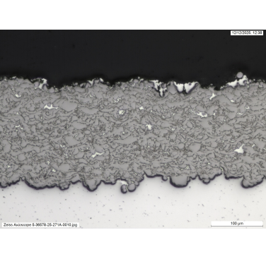 Figure 4. Example cross-sectional optical micrograph of a cold sprayed MMC with >98% W retention, deposited onto an Al substrate