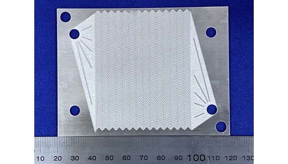 Figure 1. Photochemically etched Al-alloy shim containing zig-zag microchannels (semicircular in shape with a diameter of 500 microns per channel) and integrated headers