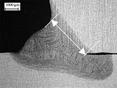 Fig.8. Transverse cross-section of laser-MAG hybrid weld showing excessive laser penetration. Throat size indicated by arrow. Scale bar = 1mm