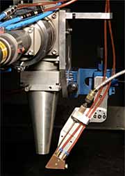 Fig.3. Photograph showing the powder delivery nozzle attached to the laser beam focusing optics incorporating a coaxial gas shield